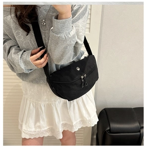 Mirror selfie showing the black half-moon nylon crossbody bag with dual zippers