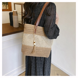 Detail of straw tote bag with wood bead tassel and leather strap in cafe setting