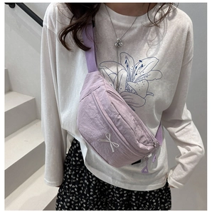 Detail of light purple nylon chest bag with white 3D bow and adjustable strap