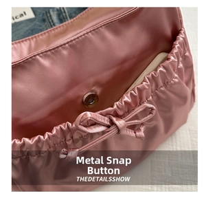 Détail de sac à main en satin rose avec fermoir magnétique et nœud décoratif élégant