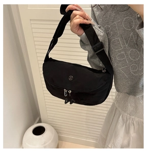 Détail du sac croissant en nylon noir avec bandoulière réglable et logo en métal