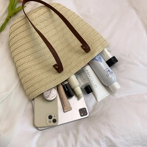 Large beige woven straw tote bag with brown leather handles and spacious interior