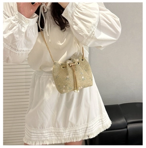 Detail of straw bucket bag with floral embroidery, pearl drawstring and gold chain strap