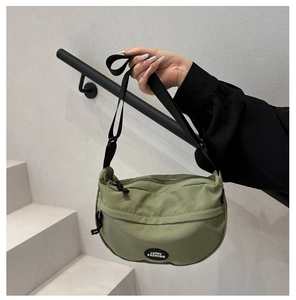 Detail of sage green nylon crescent bag with adjustable strap and fashion logo