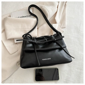 Detail of black PU leather shoulder bag with a stylish double-tie bow and fashion text