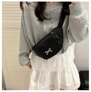 Detail of black nylon chest bag with pink bow embroidery and adjustable strap strap