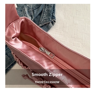 Détail de la fermeture éclair en métal argenté sur un sac à bandoulière en satin rose