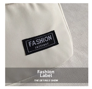 Detail of light beige canvas bag featuring a black Fashion Instinct woven label