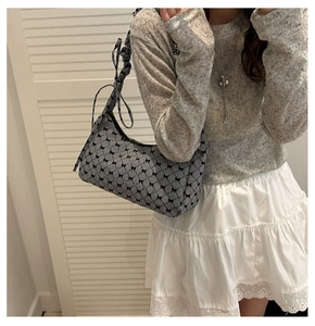 Detail of checkered shoulder bag featuring black ribbon bow and ruffled strap design