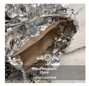 Detail of silver sequin bucket bag with metal chain strap and magnetic snap closure