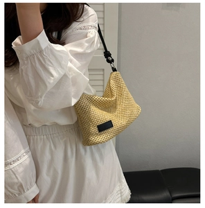 Close-up of beige woven hobo bag with black leather strap and brand patch on the side