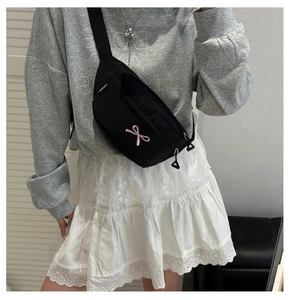 Close-up of black crossbody chest bag with pink bow embroidery and adjustable strap