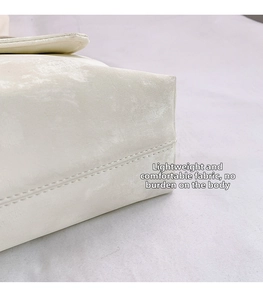 Detail of off-white suede crossbody bag showing textured fabric and neat stitching