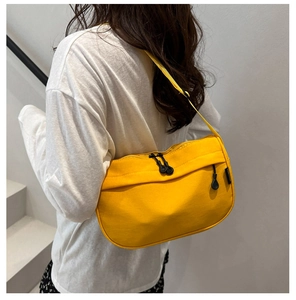 Detail of a bright yellow nylon crossbody bag featuring double zippers and black drawstrings