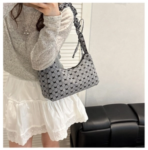Detail of gingham shoulder bag with black bow patterns and ruffled strap design