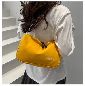 Detailed back view of a bright yellow canvas handbag with a striped woven strap