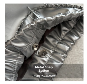 Detail of silver metallic textured handbag with magnetic snap closure and metal chain strap