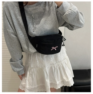 Detail of black nylon waist bag featuring pink bow embroidery and adjustable strap