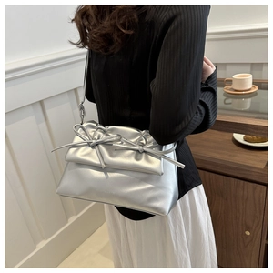 Detail of silver metallic shoulder bag with bows shown in a cozy lifestyle setting