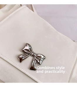 Close-up of a cream faux leather tote bag featuring a polished silver metallic bow buckle