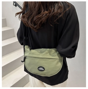 Detail of green crescent crossbody bag with LUCKY FASHION logo and adjustable strap