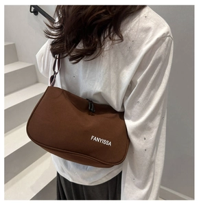 Sac bandoulière marron demi-lune avec sangle tricolore porté par un mannequin