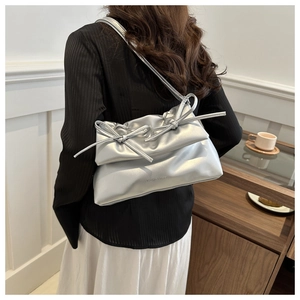 Detail of silver metallic shoulder bag with pleated texture and decorative bows