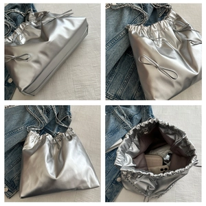 Detail view of silver pleated tote with metal chain and bow, showing interior capacity