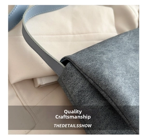 Detail of grey textured leather tote bag showing fine stitching and strap connections