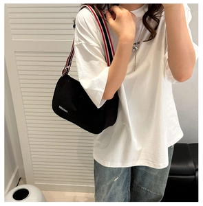 Détail du sac bandoulière en toile noire avec sangle ruban rayée rouge blanc bleu