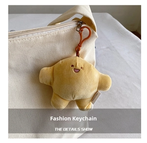 Detail of yellow plush charm with embroidered smile face attached to canvas bag