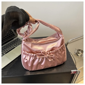 Gros plan d'un sac en satin rose avec des anses plissées et un détail de nœud décoratif