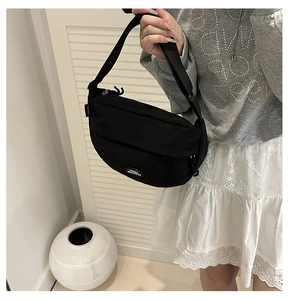Detail of a black nylon crescent crossbody bag with a white Lucky Fashion logo patch