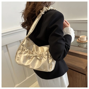 Détail de la texture d'un sac bandoulière en satin froncé avec un nœud délicat