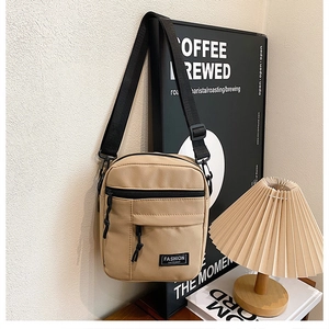 Detail of khaki canvas shoulder bag with black strap and Fashion Instinct logo