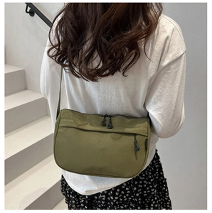 Detail of army green nylon crossbody bag with side woven label and durable zipper