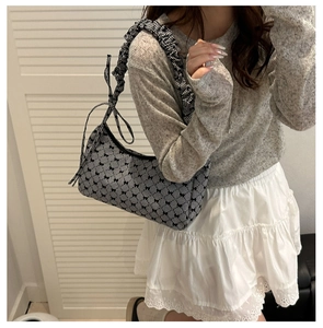 Detail of canvas shoulder bag with ruffle strap and black and white bow print pattern