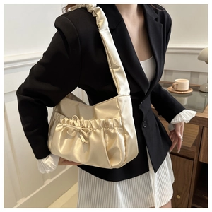 Détail d'un sac à main en satin doré champagne avec plis élégants et nœud décoratif