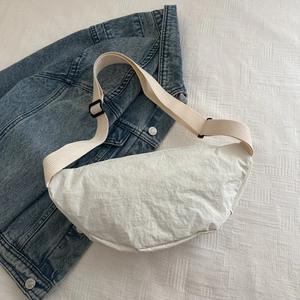 Sac bandoulière demi-lune blanc en nylon avec sangle réglable sur veste en jean