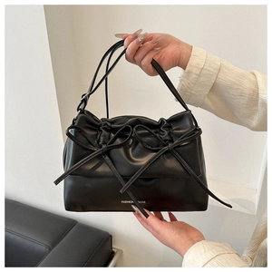Detail of a black leather tote bag featuring a ribbon bow and Fashion Bags text logo