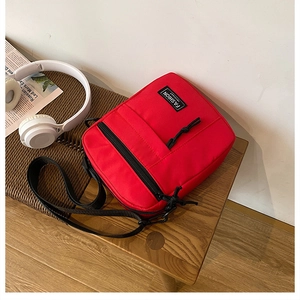 Detail of red canvas mini crossbody bag with Fashion Instinct logo and black zippers