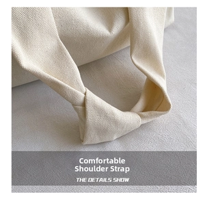 Detail of wide knotted shoulder strap on minimalist cream canvas tote bag