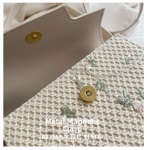 Detail van handgeweven strooien tas met bladborduurwerk en een magnetische sluiting