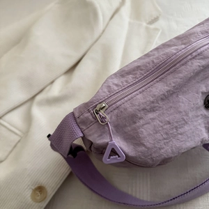 Borsa a tracolla in nylon lavanda su blazer bianco con texture increspata e zip triangolare
