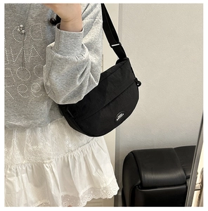 Detail of a black crescent nylon crossbody bag with an adjustable wide fabric strap