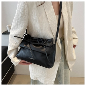 Macro detail of soft black PU leather tote with drawstring bow and logo lettering