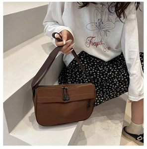 Detail view of a dark brown canvas tote bag with double zippers worn by a model
