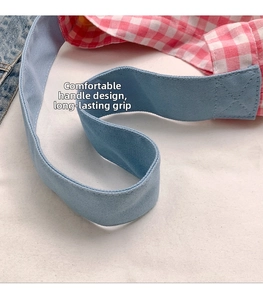 Detail of light blue canvas handle and pink-white checkered stitching on a tote bag