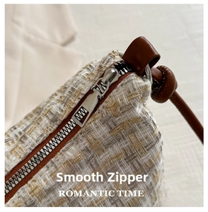 Close-up of smooth silver zipper and textured plaid tweed fabric on tote bag
