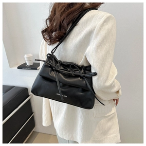 Detail of a black leather shoulder bag featuring a stylish drawstring bow design
